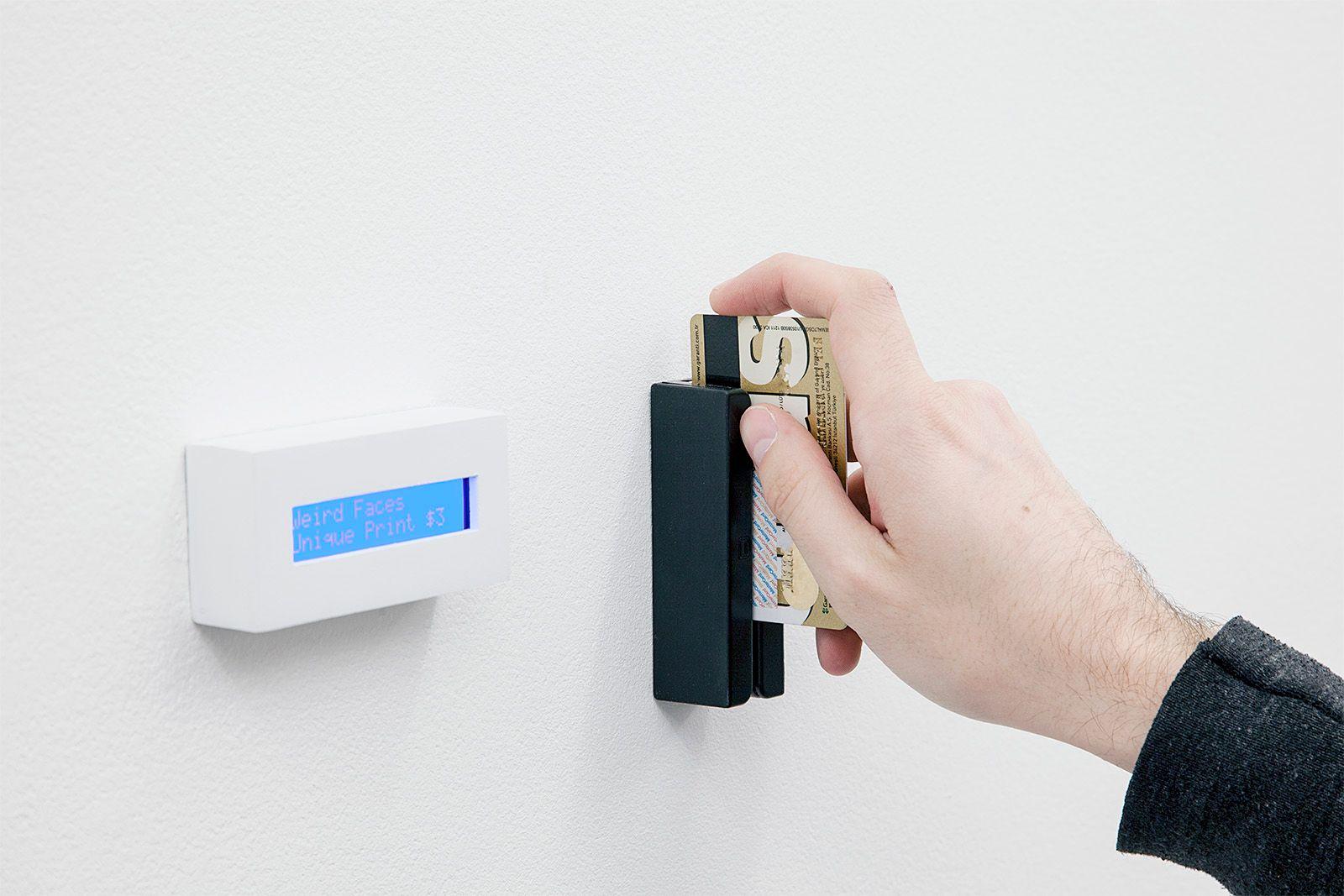 There is a light skinned hand swiping a credit card on the display. On the left of the card swiper is a small rectangular blue screen-like object. The text is illegible.