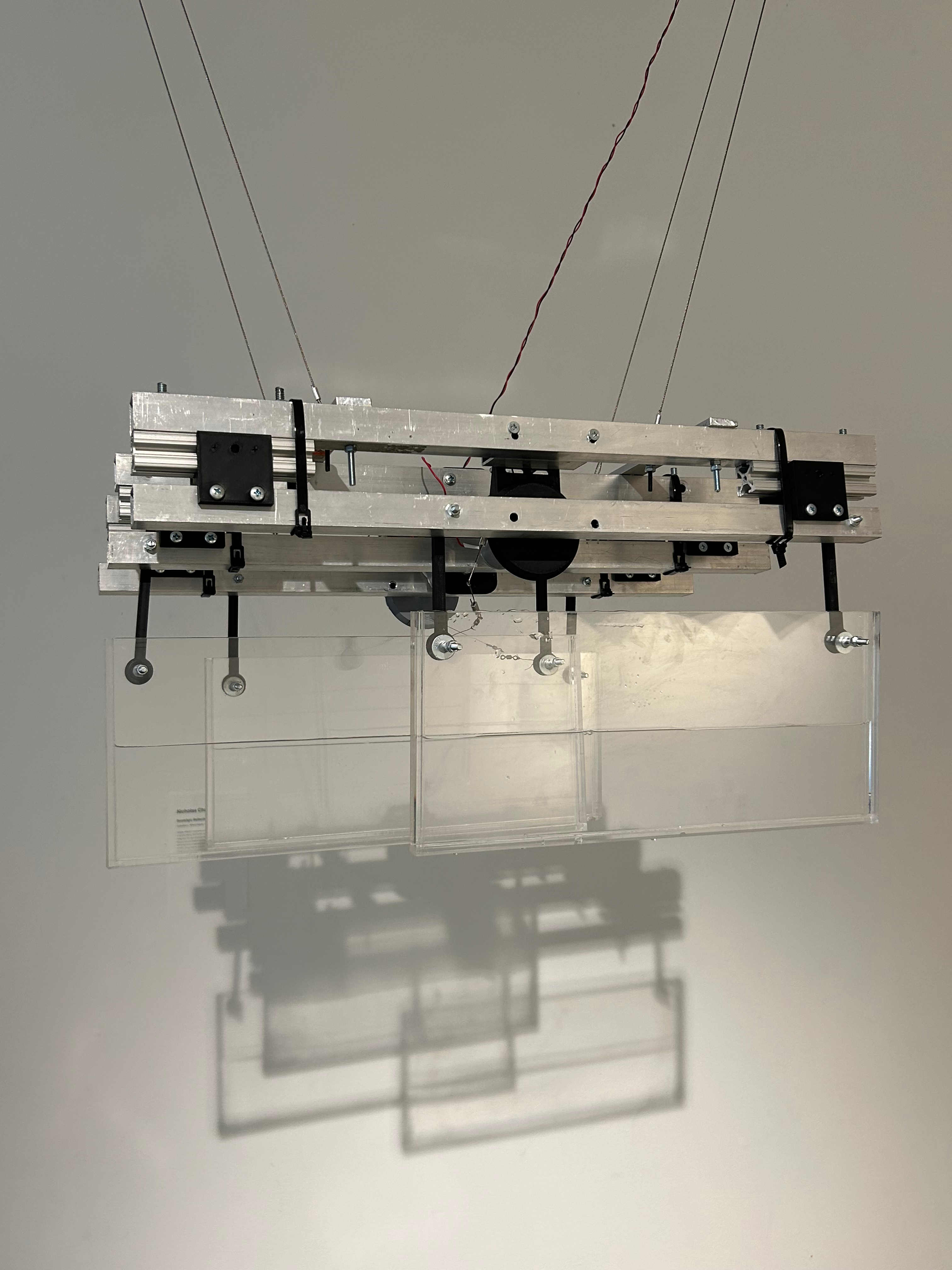 Above the CRT TV's, a metal contraption with three moving panels of plexi-glass is suspended from the ceiling.