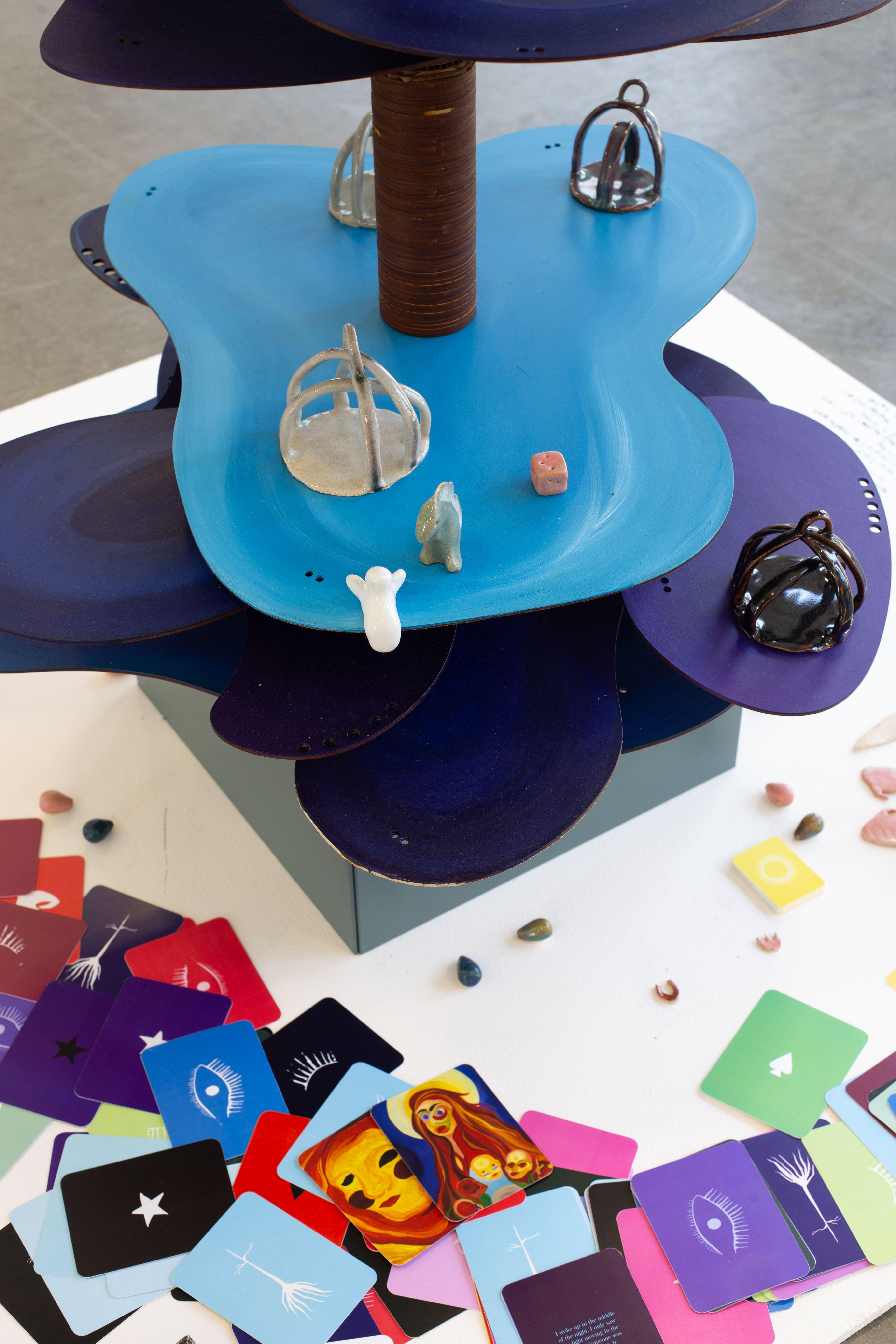 A close up of the irregular, oval shaped platforms that make up the tower, on top of which sit multiple crown-shaped game pieces.